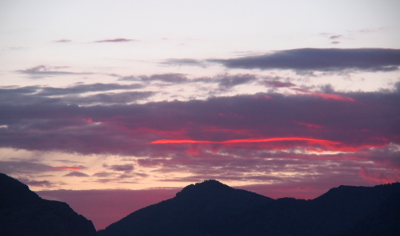 [Purplish clouds above the mountains have one long red streak across the sky in them.]